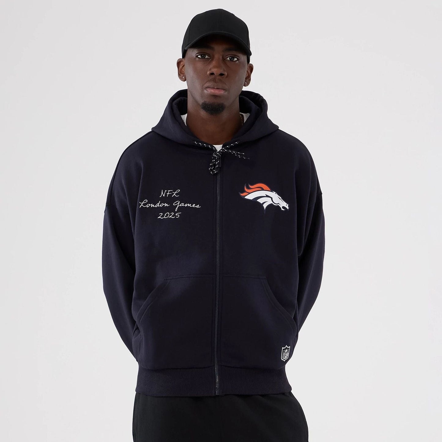 The Male model is wearing Denver Broncos NFL International Series Games 2025 Navy Premium Pullover Hoodie  1