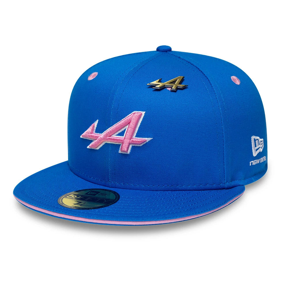 Alpine Racing Summer League Blue New Era 59FIFTY Fitted Cap, front view showing a pink embroidered A logo on the blue crown, a gold pin above, pink top button and eyelets, and a blue visor with a gold 59FIFTY size sticker.