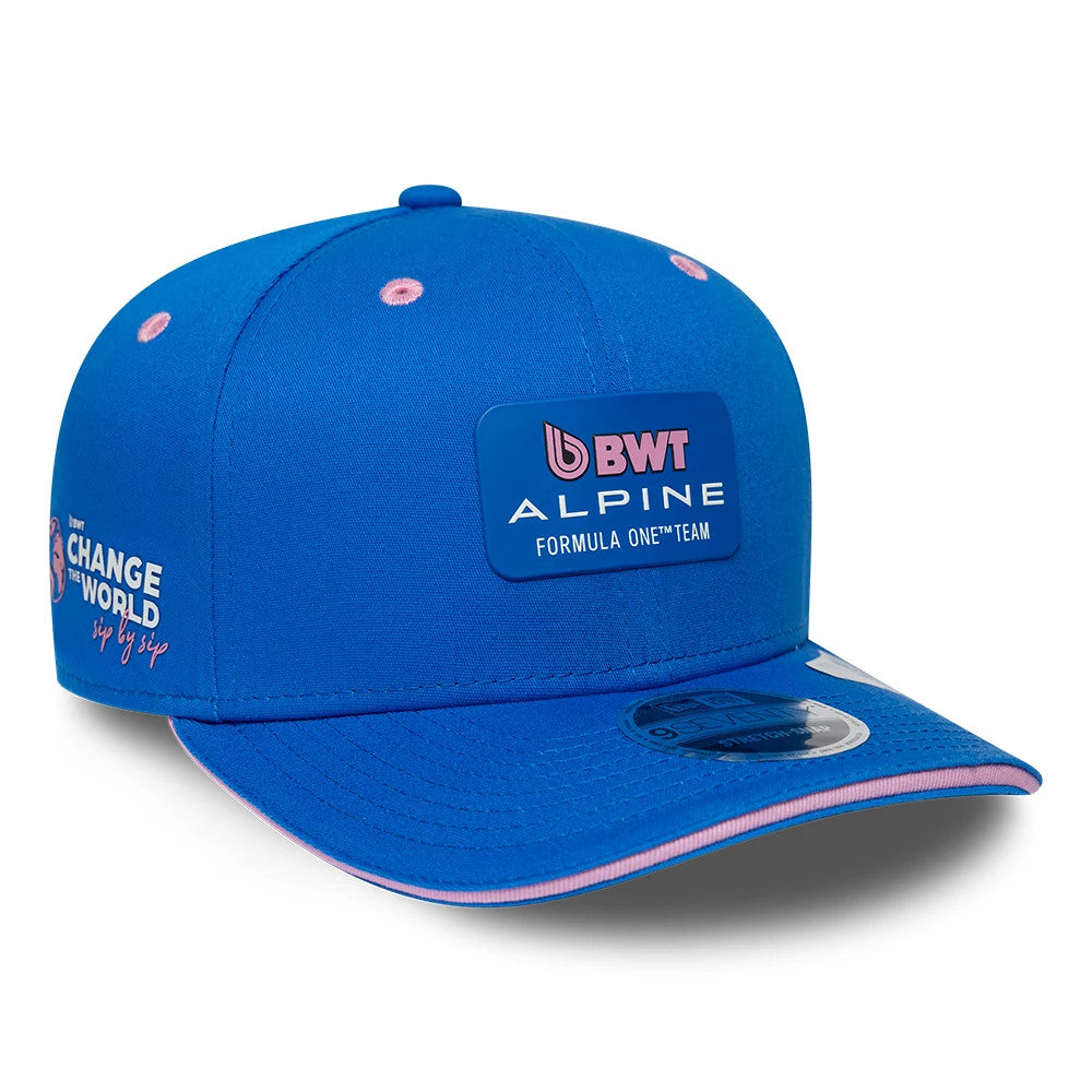 Alpine Racing Team Blue New Era 9SEVENTY Stretch Snap Adjustable Cap, three-quarter view showing the raised pink and white embroidered BWT Alpine Formula One Team logo on the front panel, with a curved visor featuring a 9SEVENTY size sticker.