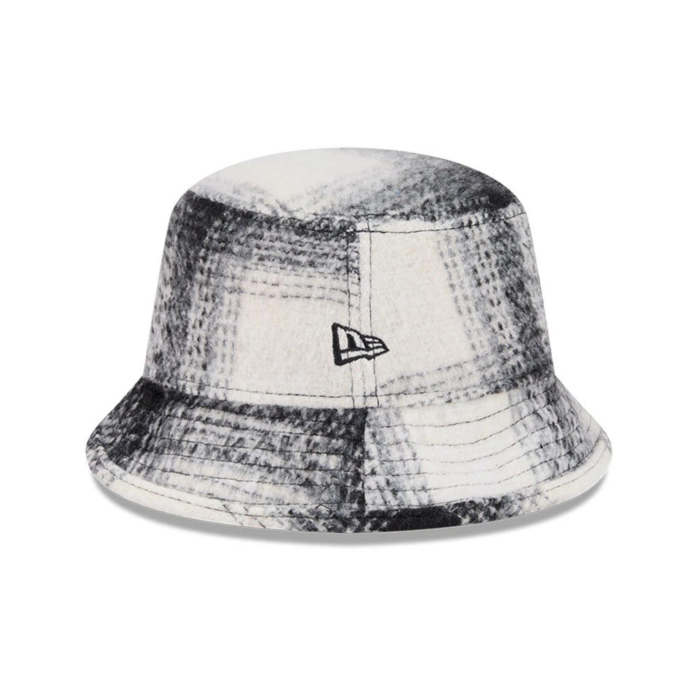 New Era White & Black Plaid Bucket Hat, three-quarter view showing the black embroidered New Era flag logo on the side, with a soft visor and a textured plaid pattern in shades of white and black.