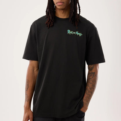New Era Rick And Morty Portal Gun Black T-Shirt, front view on a model showing the black base with a small, embroidered Rick and Morty logo in green and white on the left chest, styled with casual black trousers.