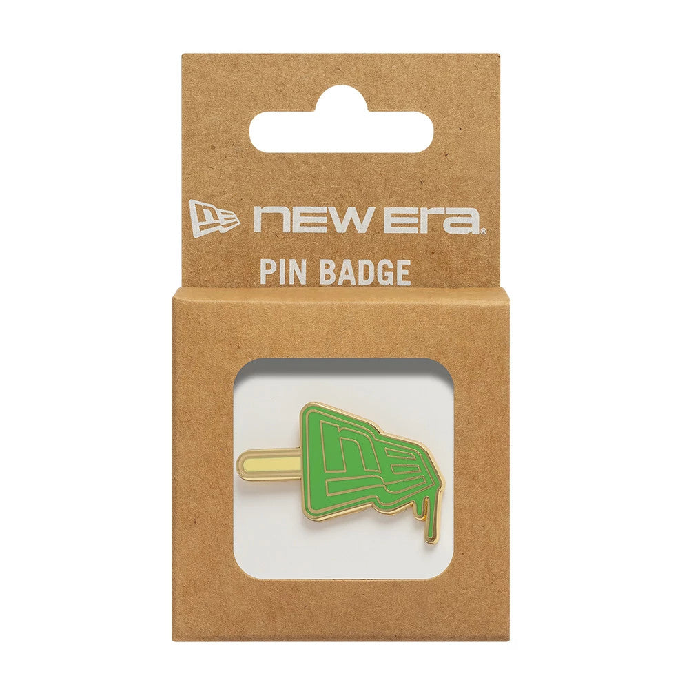 New Era Lolly Open Green Pin Badge, front view showing a green lolly-shaped pin with a gold outline and dripping detail, set against kraft packaging with the New Era logo and 'Pin Badge' text prominently displayed above the badge window.