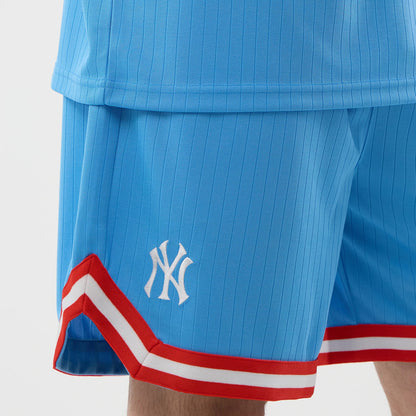 New Era New York Yankees MLB Arch Pastel Blue Oversized Shorts, three-quarter view showing the light blue fabric with vertical pinstripes, the white embroidered Yankees logo on the left leg, and red and white striped trim along the hem.