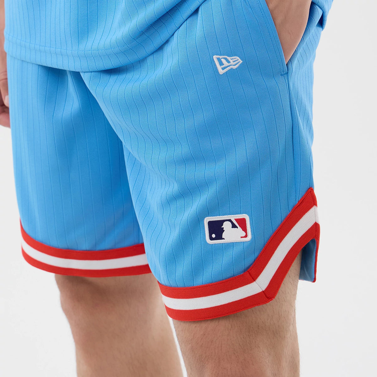 New Era New York Yankees MLB Arch Pastel Blue Oversized Shorts, side view showing pastel blue shorts with vertical pinstripes, a white embroidered New Era logo above the pocket, and an MLB Batterman logo above a red and white striped hem.