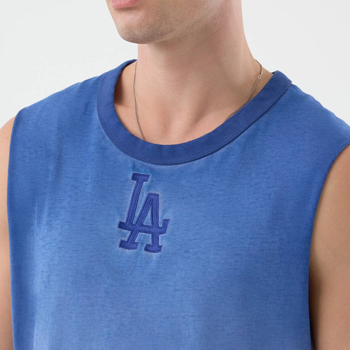 New Era LA Dodgers MLB Washed Logo Pastel Blue Vest, front view on a model showing the dark blue embroidered LA logo centred below the round neckline, with soft sleeveless edges and a pastel blue fabric texture.