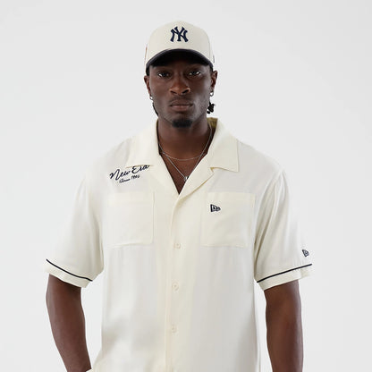 The model is wearing this New Era Graphic Revere Short Sleeve Shirt in open white. 3