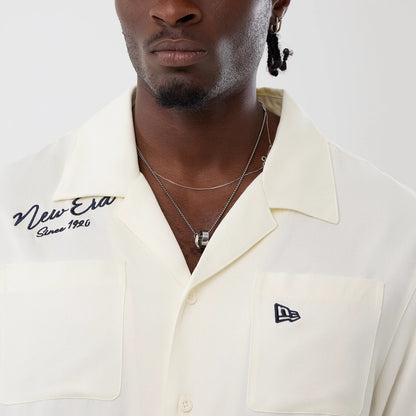 The model is wearing this New Era Graphic Revere Short Sleeve Shirt in open white. 5