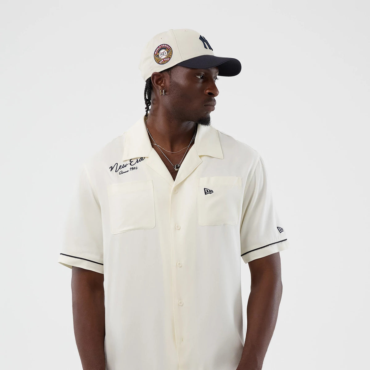 The model is wearing this New Era Graphic Revere Short Sleeve Shirt in open white. 7