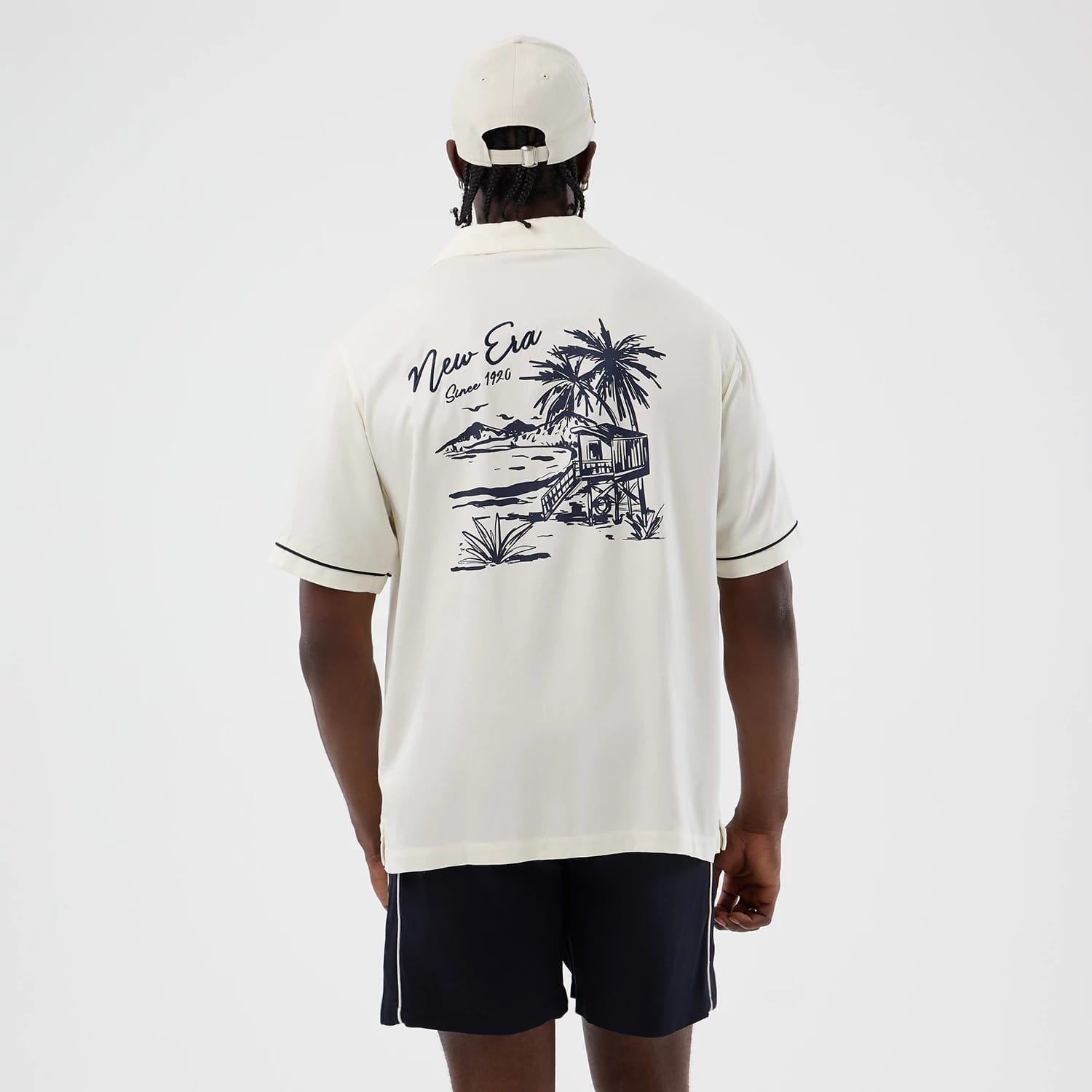 The model is wearing this New Era Graphic Revere Short Sleeve Shirt in open white. 2