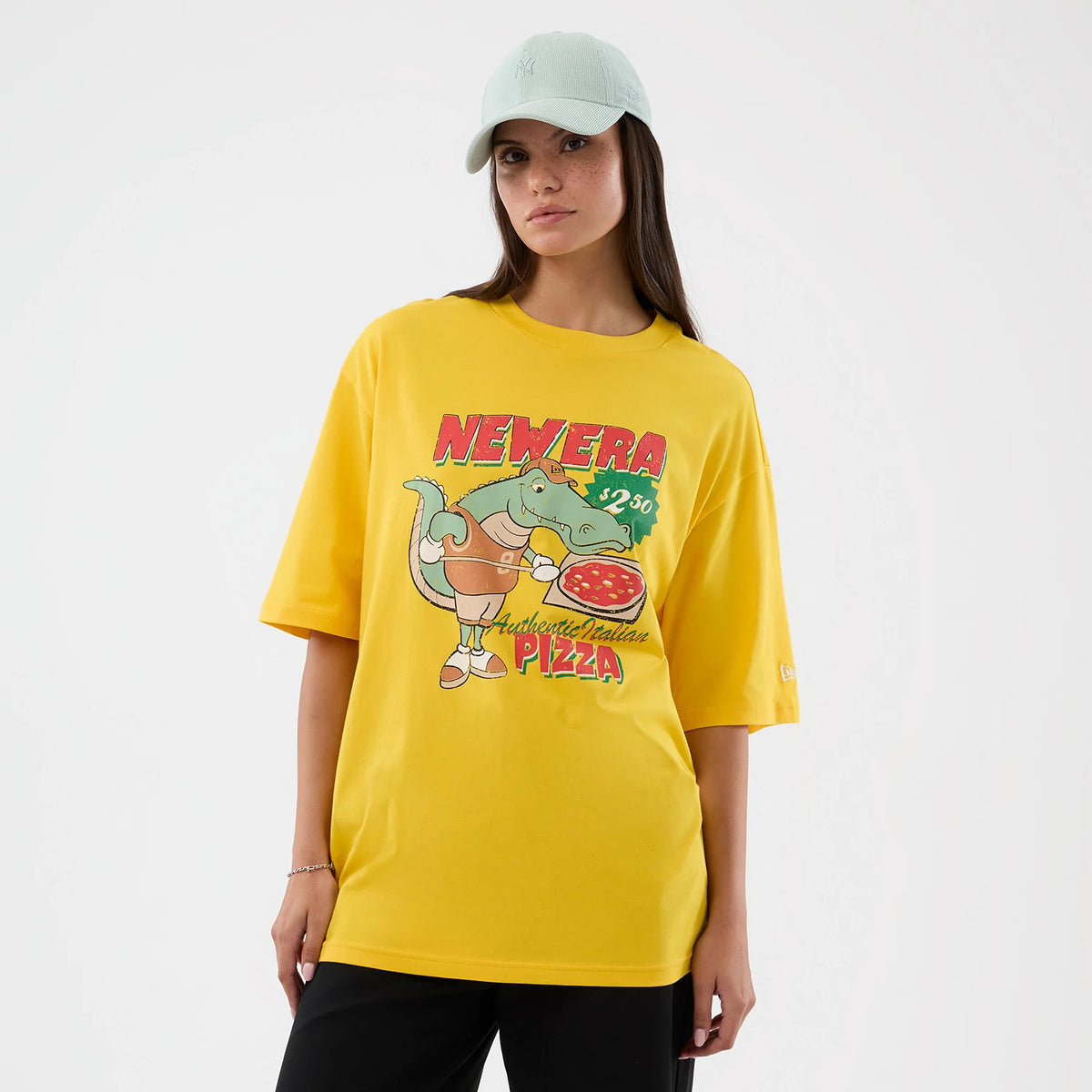 New Era Alligator Character Graphic Yellow T-Shirt, front view on-model showing an alligator holding a pizza with NEWERA and price text above, Authentic Italian Pizza below, and a small embroidered New Era logo on the left sleeve.