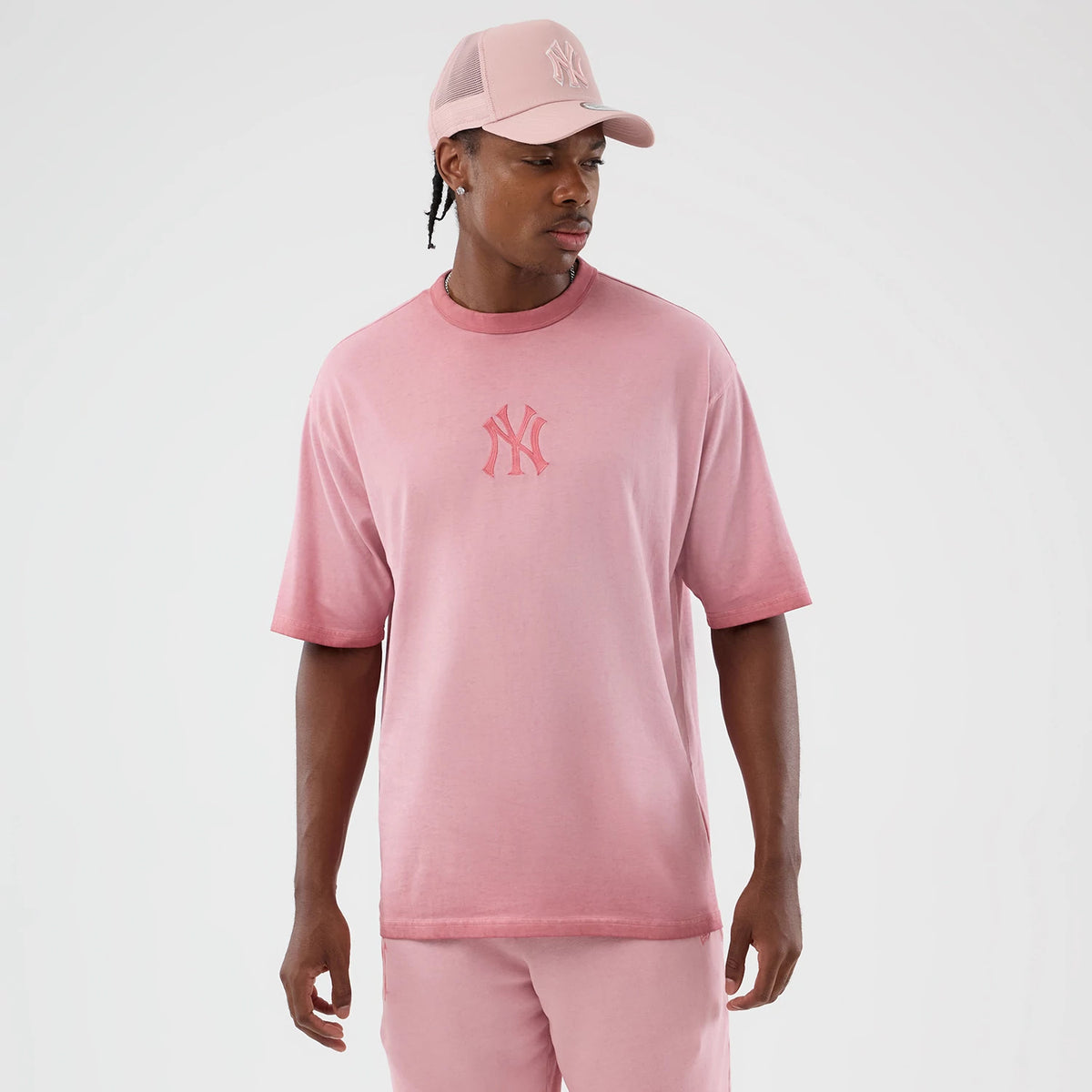 New Era New York Yankees MLB Washed Logo Pastel Pink T-Shirt, front view on-model showcasing a soft pastel pink hue with an embroidered team logo centred on the chest, styled with matching pink shorts and a cap featuring a raised logo.