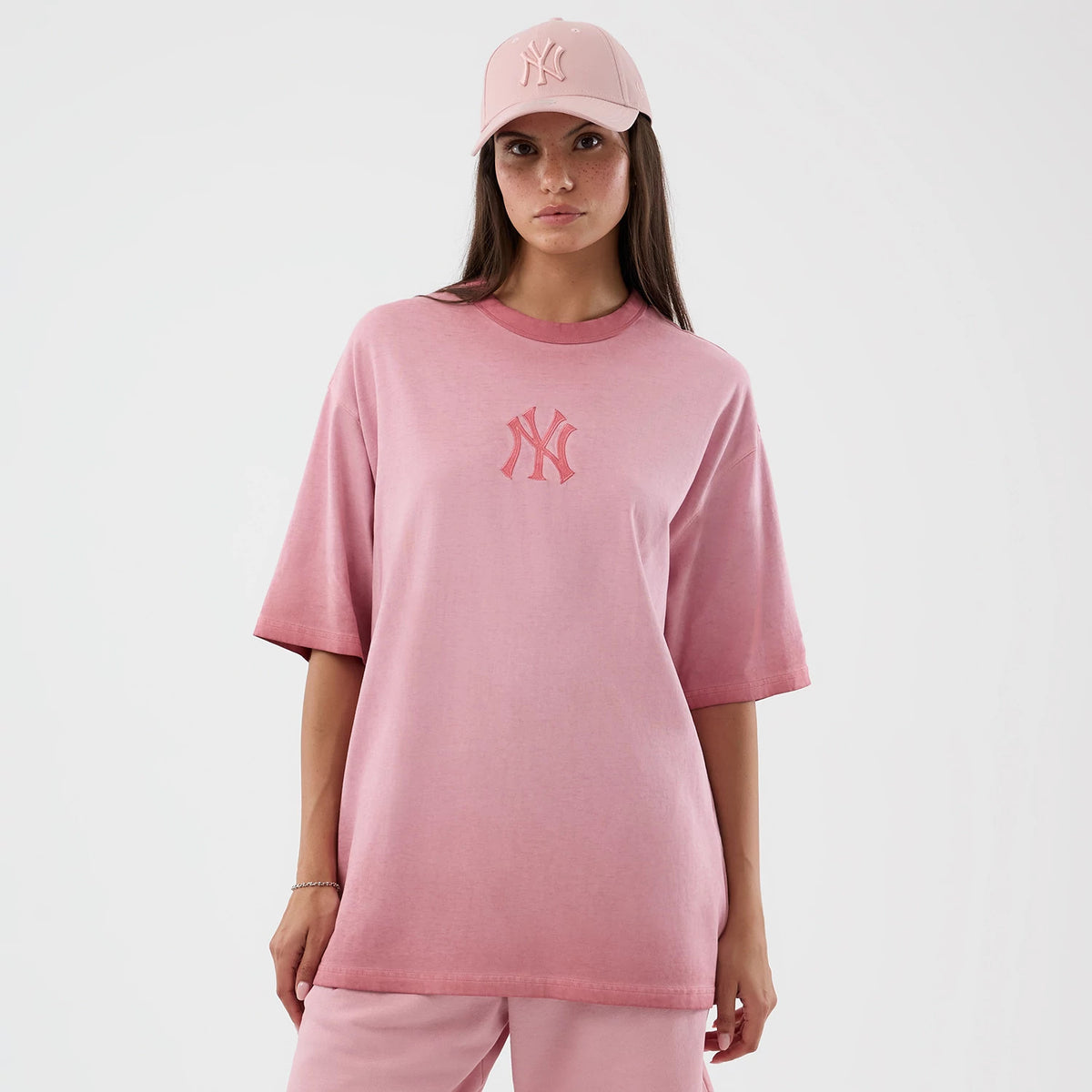 New Era New York Yankees MLB Washed Logo Pastel Pink T-Shirt, front view on a model styled with a matching pastel pink cap, featuring the raised New York Yankees logo on the chest and a loose, casual fit that falls below the hips.