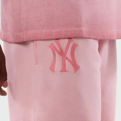 New Era New York Yankees MLB Washed Logo Pastel Pink Shorts, front view showing a large embroidered NY logo on the left thigh, the soft pastel pink fabric contrasting with a slightly darker pink shirt edge above the waistband.