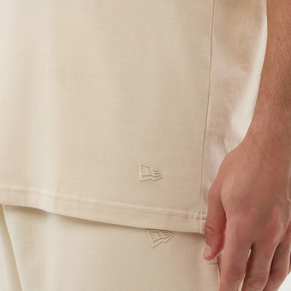 New Era Chicago Bulls NBA Core Plus Light Beige Vest, side view on a model showing the New Era flag logo embroidered near the hem, with the beige fabric appearing and the relaxed fit complementing matching shorts.