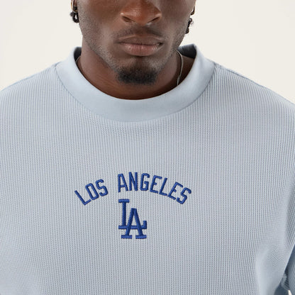 New Era LA Dodgers MLB Waffle Pastel Blue T-Shirt, front view showing blue embroidered Los Angeles lettering in an arc above the LA logo on a textured pastel blue fabric, styled casually on a model with a thick neckline and short sleeves.