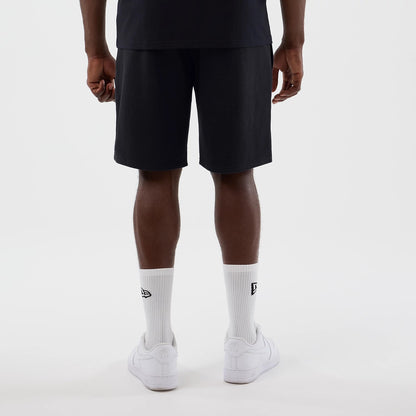 New Era LA Lakers NBA Core Plus Navy Shorts, back view on a model with a plain black T-shirt, showcasing the solid navy colour and mid-length design, complemented by white socks featuring an embroidered New Era logo and plain white trainers.