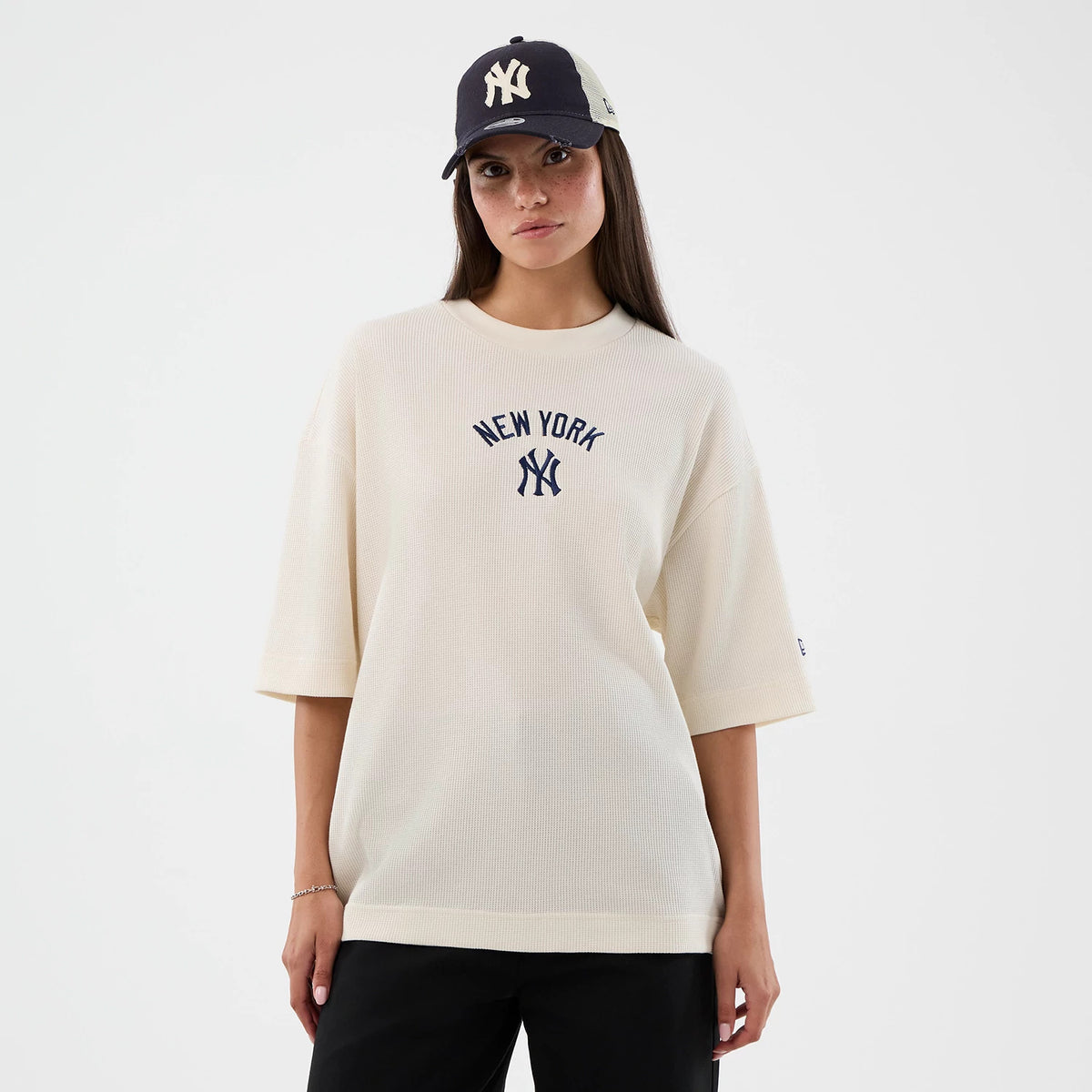 New Era New York Yankees MLB Waffle Open White T-Shirt, front view on a model showing a relaxed fit and navy embroidered New York Yankees logo at the centre chest, contrasted by black trousers and a matching cap.