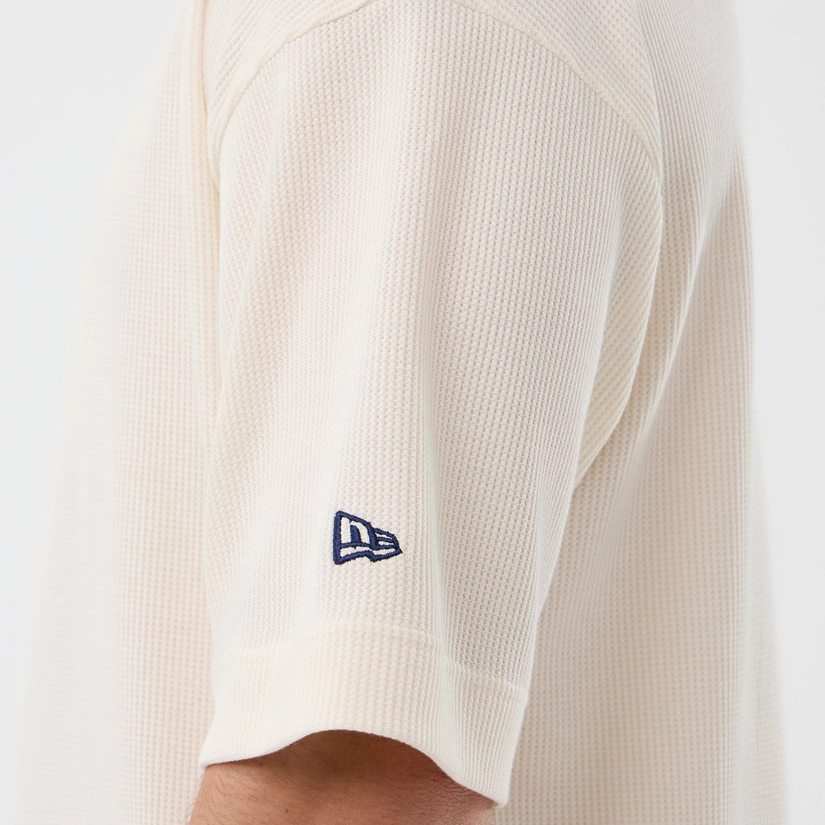 New Era New York Yankees MLB Waffle Open White T-Shirt, side view showing the textured waffle pattern on the white fabric, with a navy embroidered New Era flag logo located on the lower sleeve, enhancing the minimalist design.