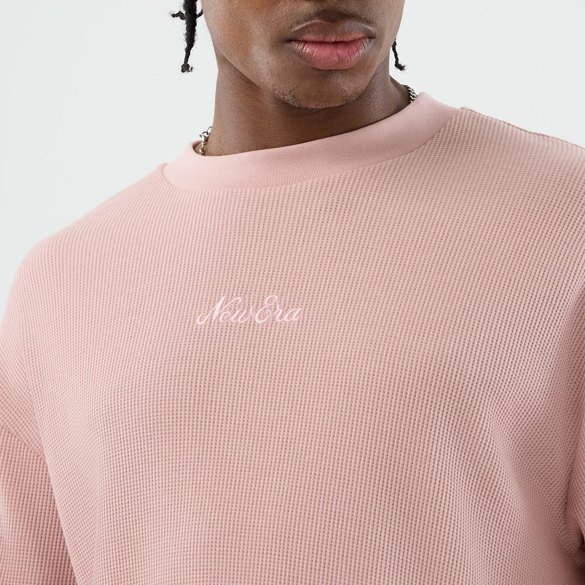 New Era Waffle Pastel Pink T-Shirt, front view on a model showing the soft pink textured fabric with a knitted pattern, featuring a white embroidered New Era logo across the chest set beneath the rounded collar.