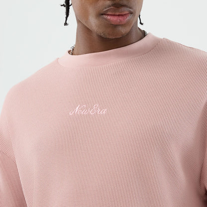 New Era Waffle Pastel Pink T-Shirt, front view on a model showing the soft pink textured fabric with a knitted pattern, featuring a white embroidered New Era logo across the chest set beneath the rounded collar.