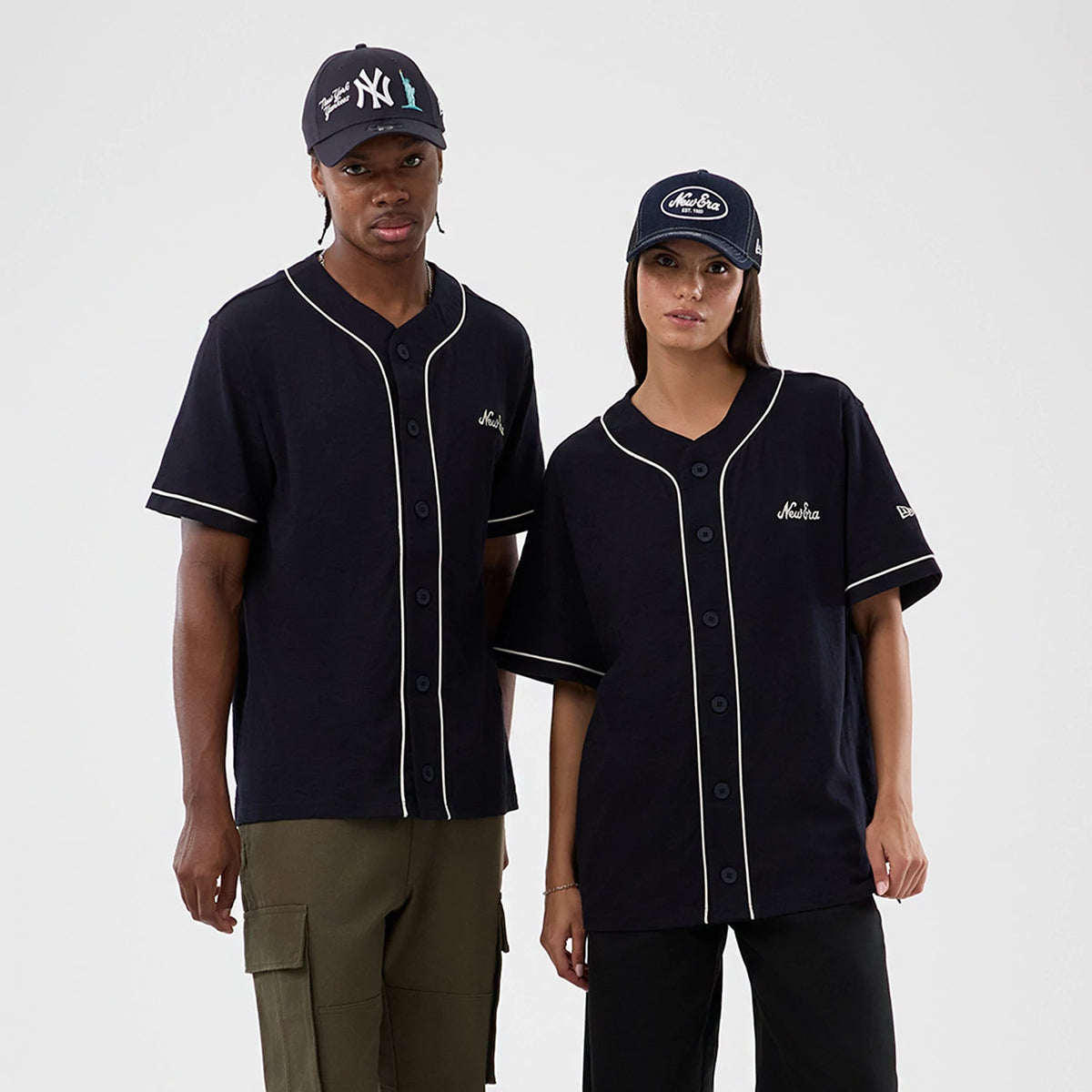 New Era Slub Navy Baseball Jersey, front view on models with a black buttoned-up design, showing white piping along the button placket and sleeves, and a New Era script logo on the left chest above the hem.