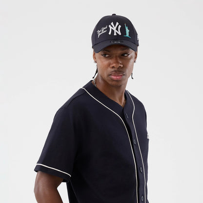 New Era Slub Navy Baseball Jersey, on-model view showing a navy jersey with white piping along the buttoned front and sleeves, worn with a matching cap featuring New York Yankees logos and the Statue of Liberty on the front panel.