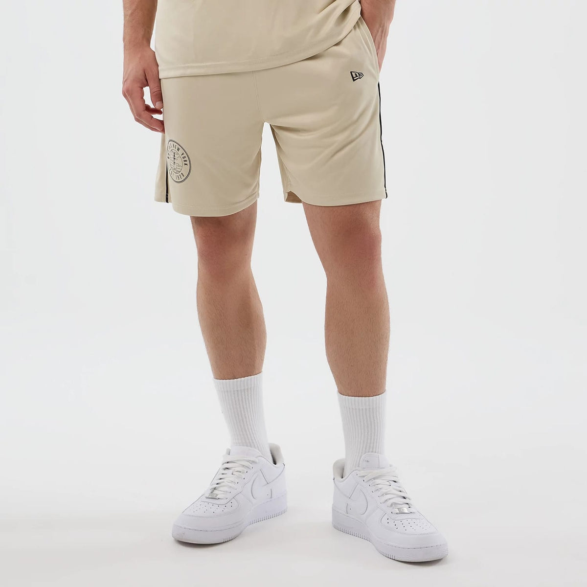 The model is wearing these New Era Football Shorts in light beige. 7