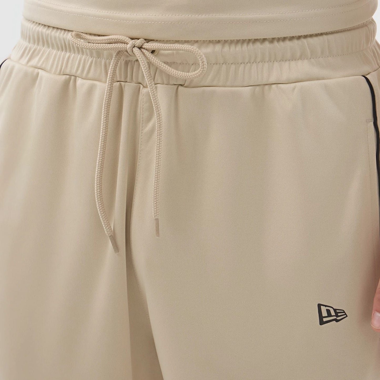 The model is wearing these New Era Football Shorts in light beige. 5