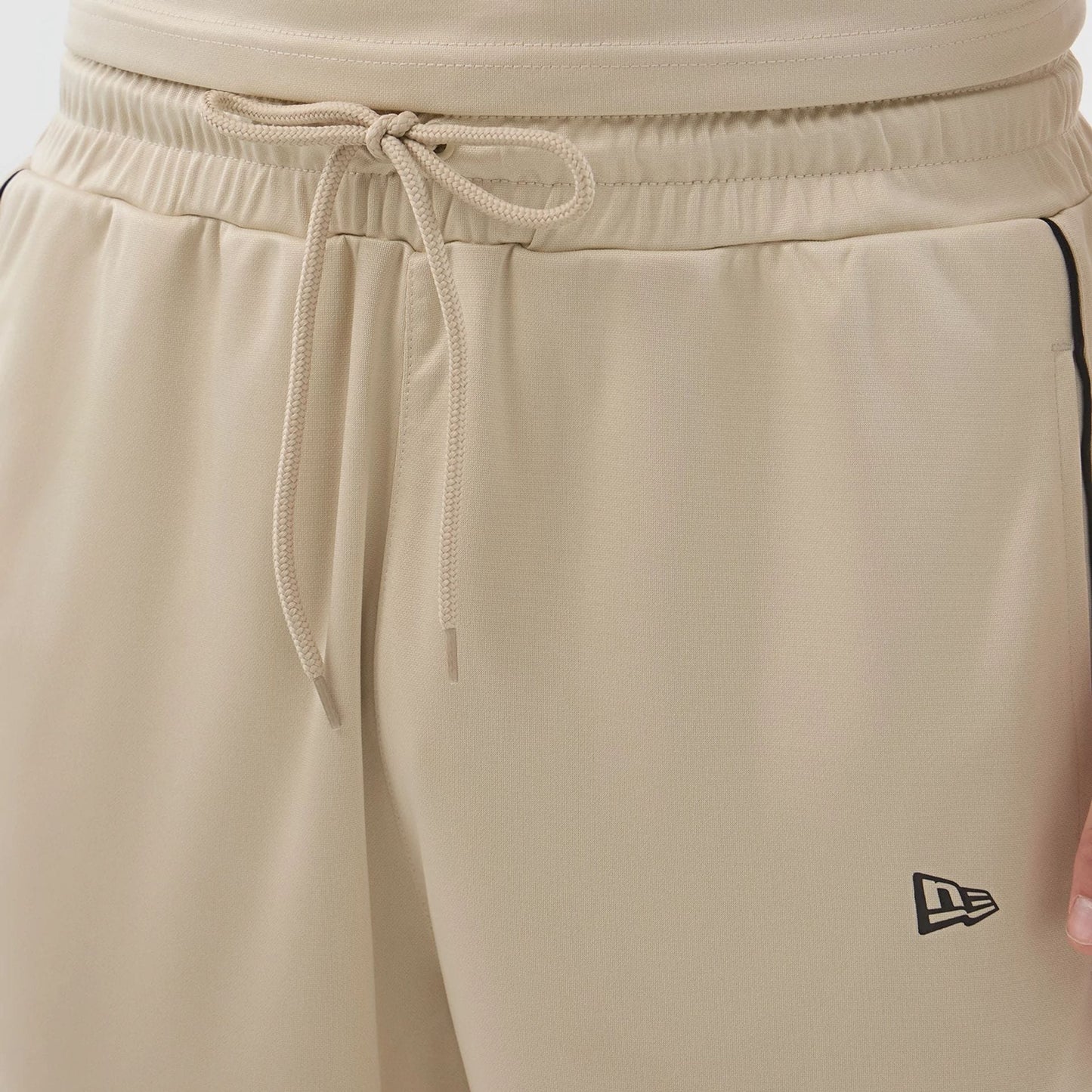 The model is wearing these New Era Football Shorts in light beige. 5