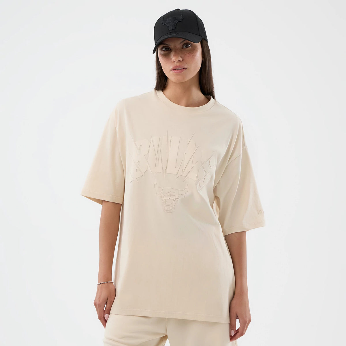New Era Chicago Bulls NBA Core Plus Light Beige Oversized T-Shirt, front view on a model showcasing the word BULLS and the bull head debossed across the chest, short sleeves, and the New Era logo embroidered on the left sleeve.