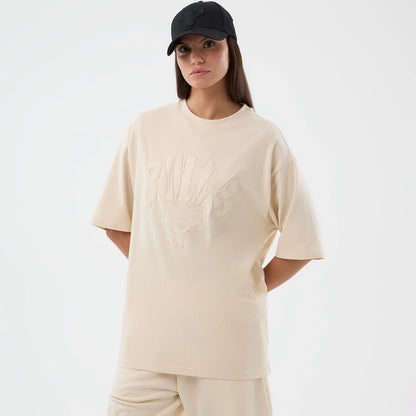 New Era Chicago Bulls NBA Core Plus Light Beige Oversized T-Shirt, front view on-model displaying a light beige oversized fit, a debossed Bulls logo graphic on the chest, and a New Era flag embroidered on the left sleeve.