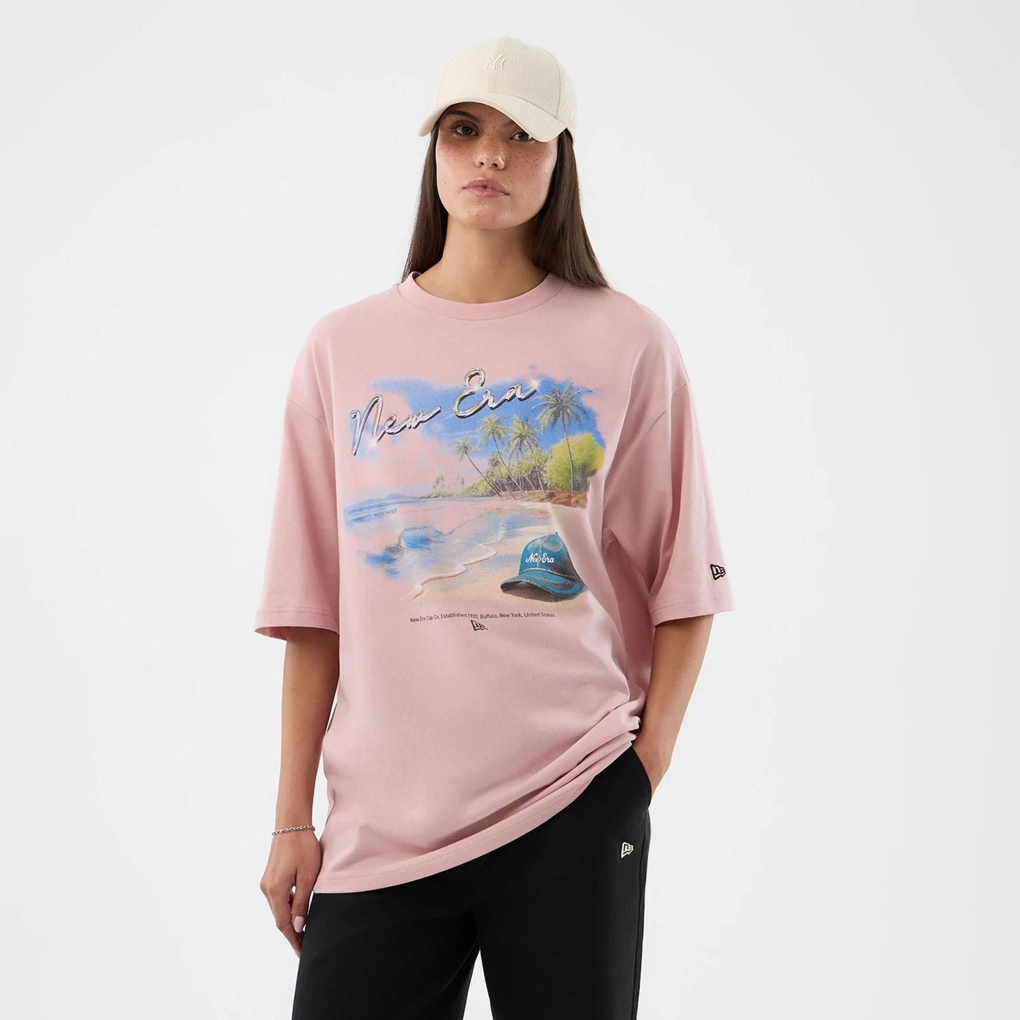 The model is wearing this New Era Beach Graphic Oversized T-Shirt in pastel pink. 4