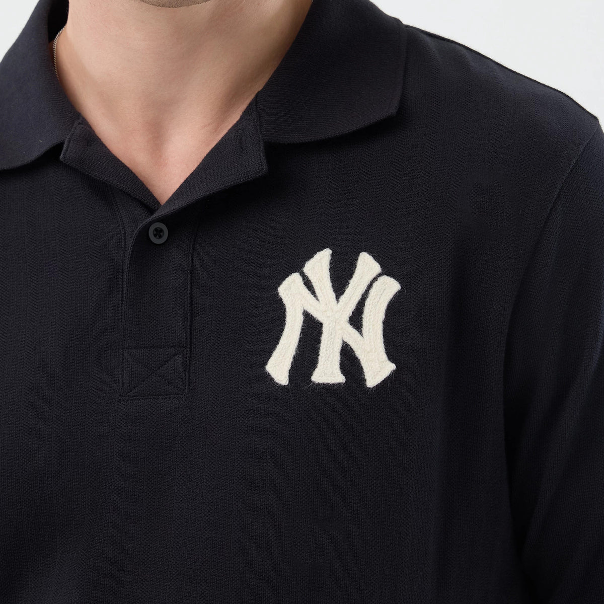 New Era New York Yankees MLB Rib Navy Polo T-Shirt, front view showing a cream embroidered New York Yankees logo prominently on the left chest, a classic polo collar with a buttoned placket below, and the navy fabric styled on a model.