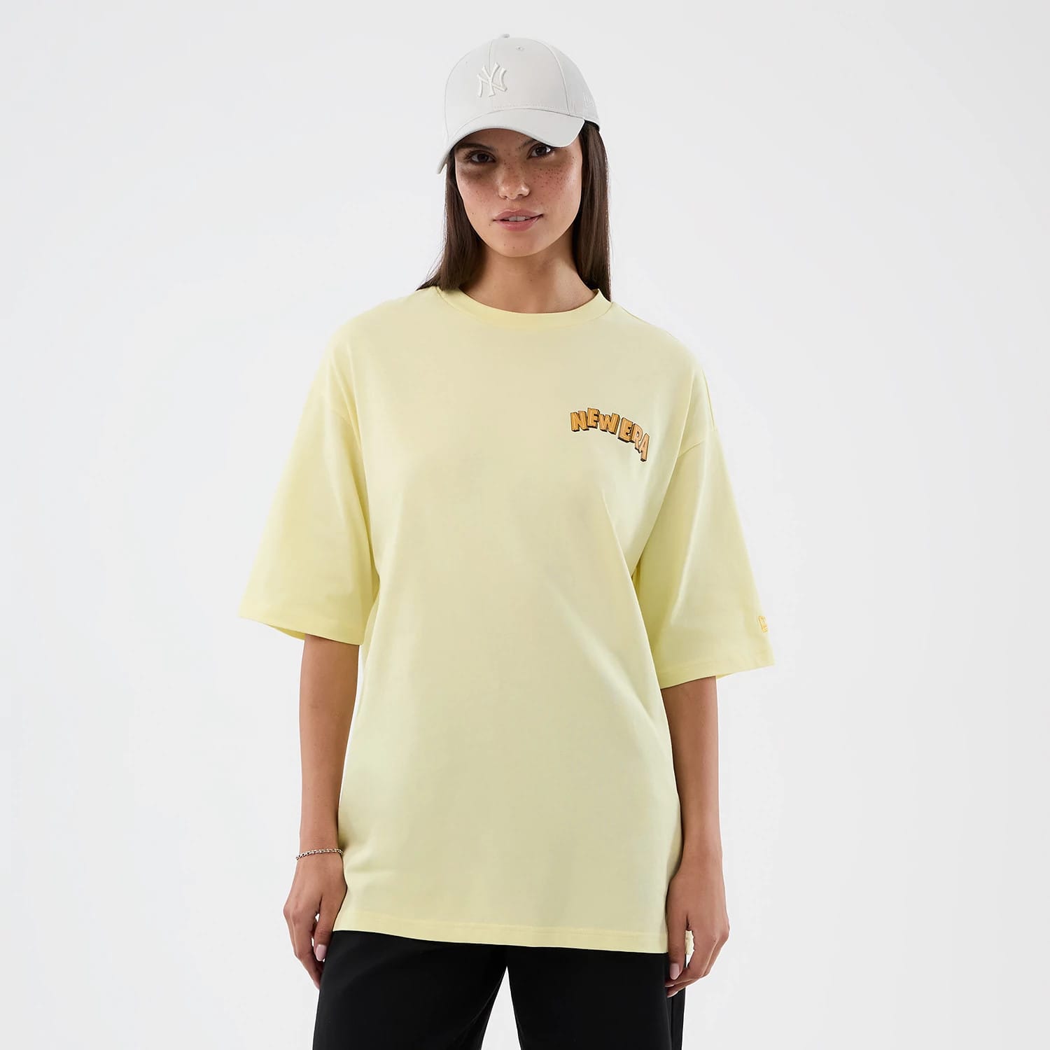 The model is wearing this New Era Fun Beach Party Graphic Oversized T-Shirt in pastel yellow. 4