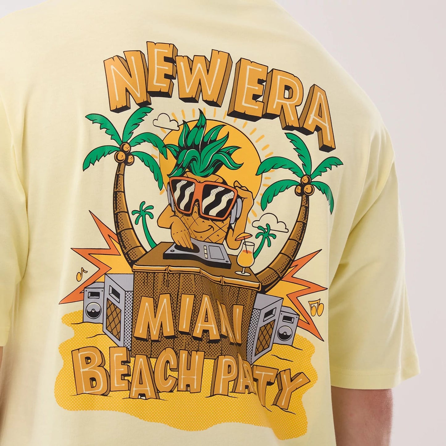 The model is wearing this New Era Fun Beach Party Graphic Oversized T-Shirt in pastel yellow. 5