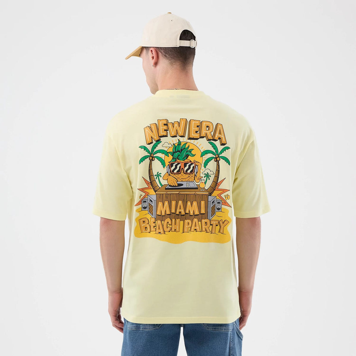 The model is wearing this New Era Fun Beach Party Graphic Oversized T-Shirt in pastel yellow. 2