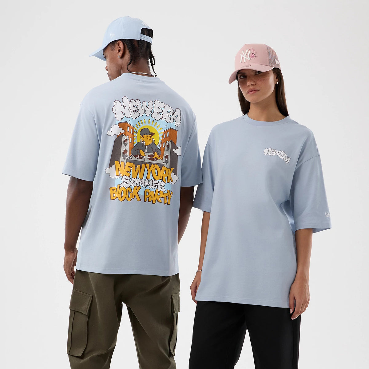 New Era Fun Block Party Graphic Pastel Blue Oversized T-Shirt, front and back view on models showing a block party graphic on the back featuring a DJ and speakers, white embroidered New Era logo on the chest and left sleeve.