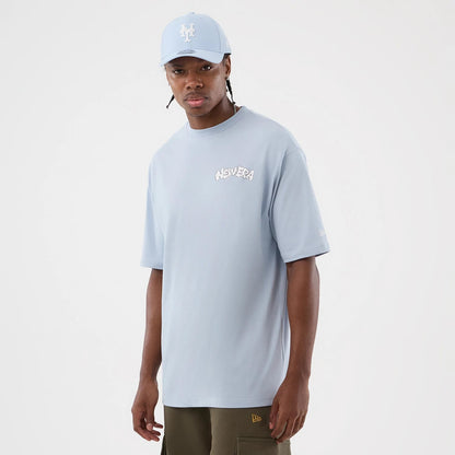 The model is wearing this New Era Fun Block Party Graphic Oversized T-Shirt in pastel blue. 3