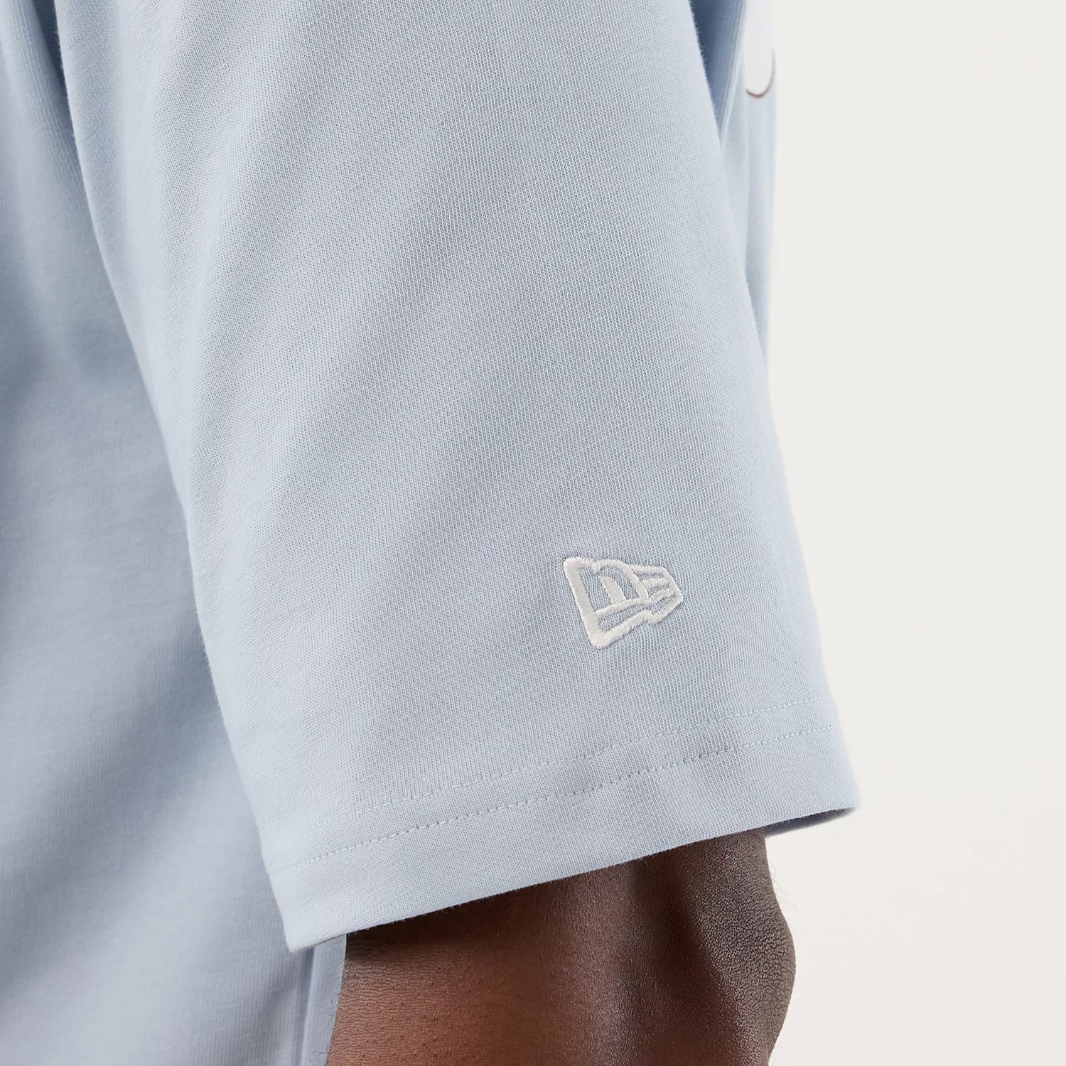 The model is wearing this New Era Fun Block Party Graphic Oversized T-Shirt in pastel blue. 7