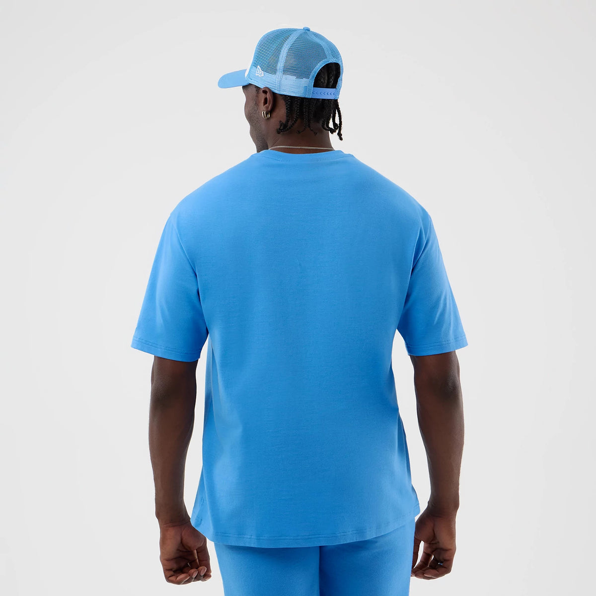 New Era New York Yankees MLB League Essential Pastel Blue Oversized T-Shirt, back view on a model styled with a matching cap, highlighting the solid pastel blue colour and loose fit of the T-shirt.
