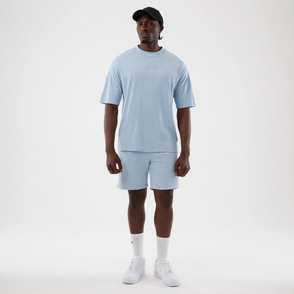 New Era LA Lakers NBA League Essential Pastel Blue Oversized T-Shirt, front view on a model featuring a embroidered Lakers logo at centre chest and relaxed fit sleeves, paired with matching pastel blue shorts and white trainers.