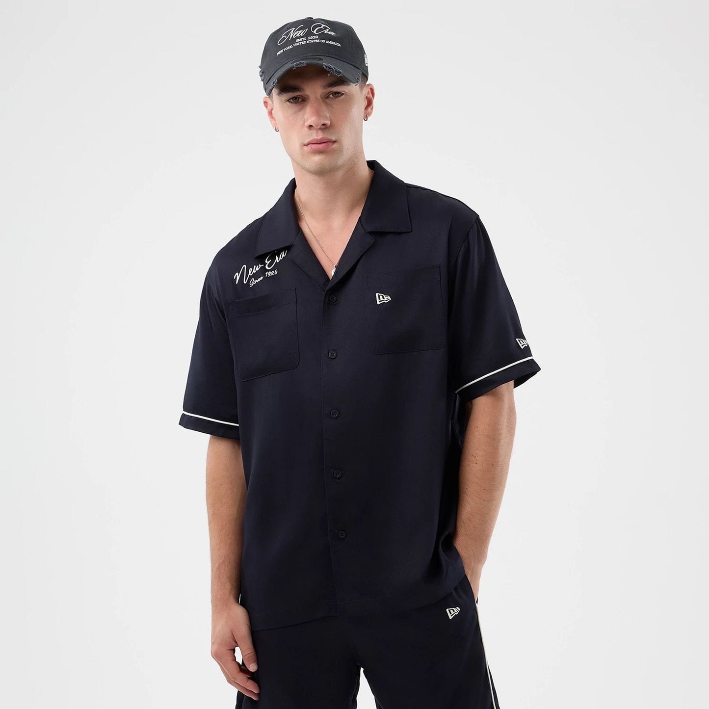 The model is wearing this New Era Graphic Revere Short Sleeve Shirt in navy. 3