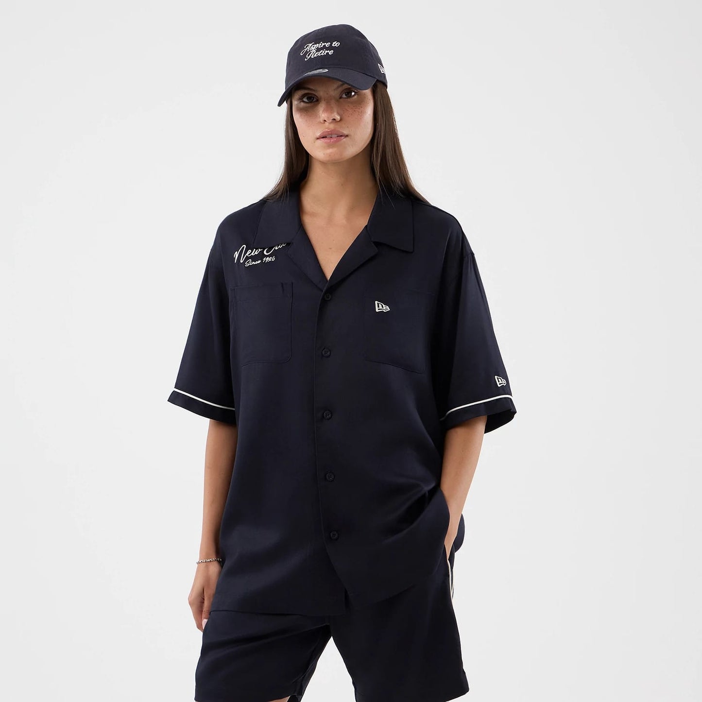 The model is wearing this New Era Graphic Revere Short Sleeve Shirt in navy. 4