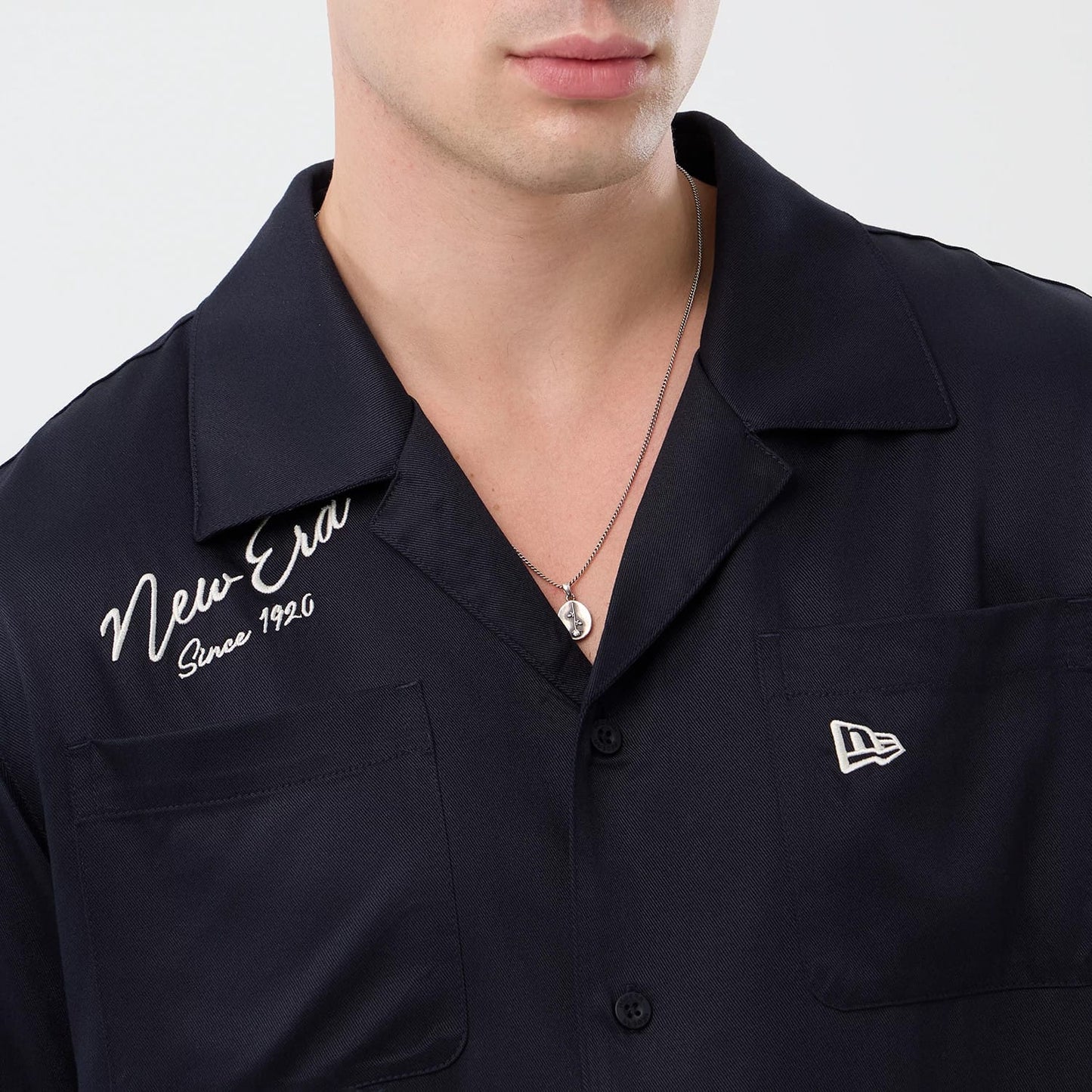 The model is wearing this New Era Graphic Revere Short Sleeve Shirt in navy. 6