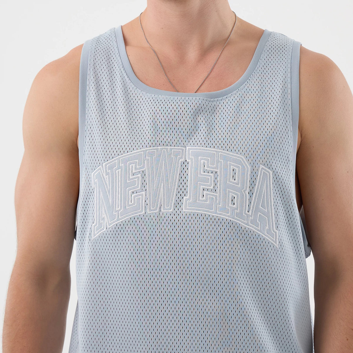 New Era Mesh Pastel Blue Oversized Tank Top, front view on a model showing the large outlined NEW ERA lettering across the chest, featuring lightweight mesh fabric and wide arm openings for a relaxed fit.