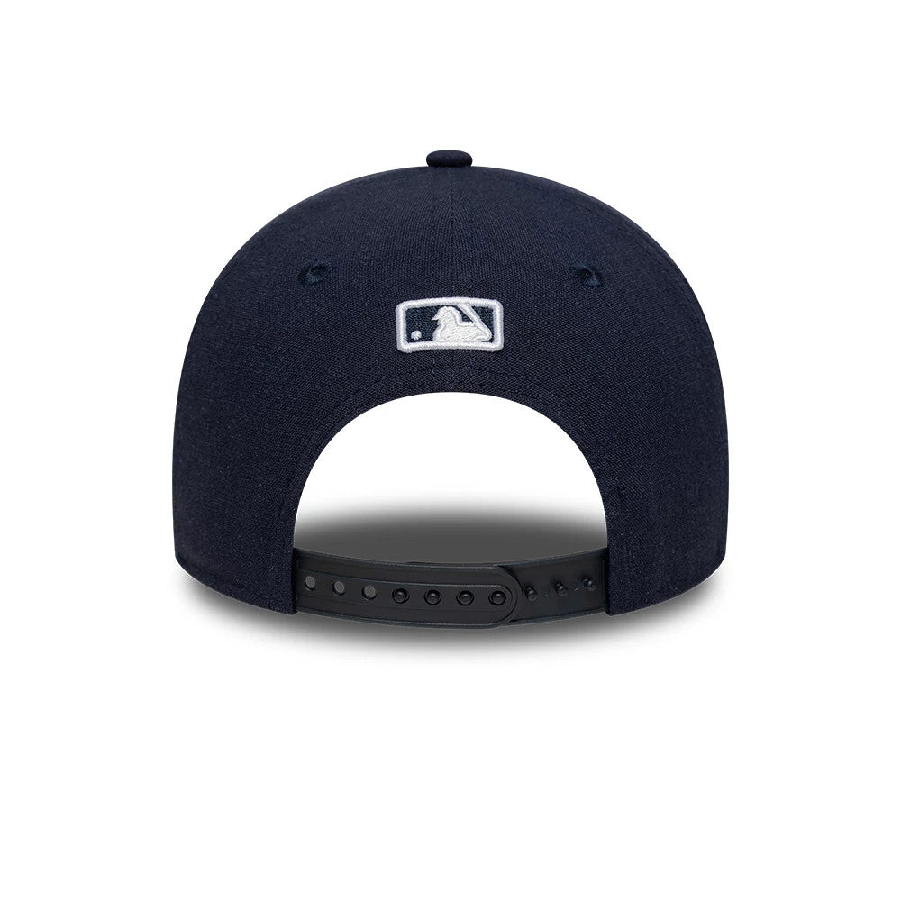 New York Yankees MLB Linen Navy New Era 9FORTY M-Crown Adjustable Cap, rear view showing the white embroidered MLB Batterman logo centred on the navy crown, with a black adjustable snap closure and matching navy fabric eyelets.