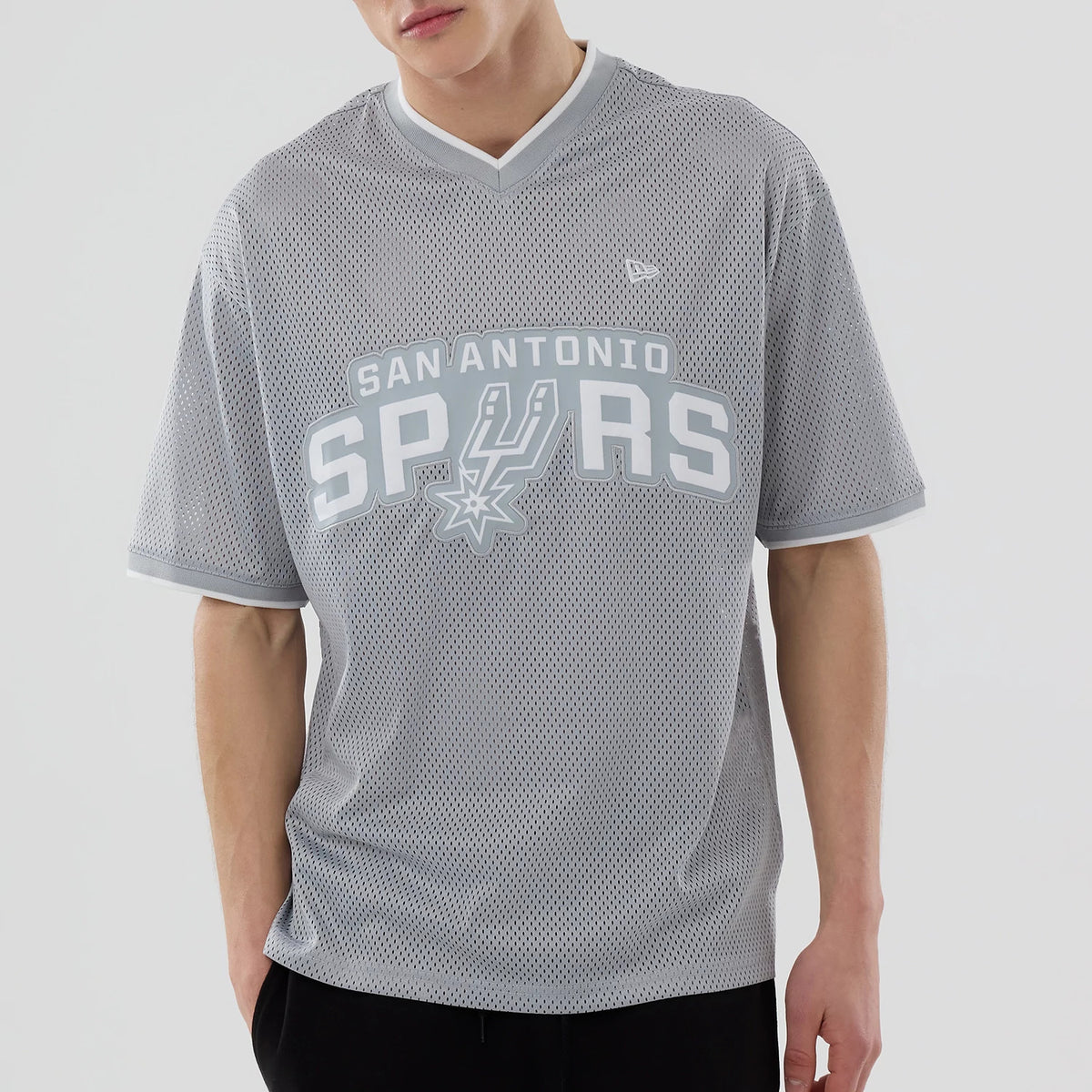 New Era San Antonio Spurs NBA Mesh Grey Oversized T-Shirt, front view on-model featuring the large white printed San Antonio Spurs lettering and emblem across the chest, a v-neck collar, and a small embroidered New Era logo on the left shoulder.