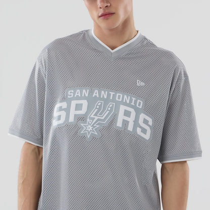 New Era San Antonio Spurs NBA Mesh Grey Oversized T-Shirt, front view on-model displaying a large white printed San Antonio Spurs logo centred across the chest, with a small embroidered New Era logo on the upper right chest and grey V-neck collar.
