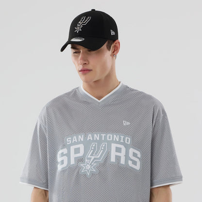 New Era San Antonio Spurs NBA Mesh Grey Oversized T-Shirt, front view on a model with a black cap, showcasing the large San Antonio Spurs lettering and logo across the chest, a V-neckline with white trim.