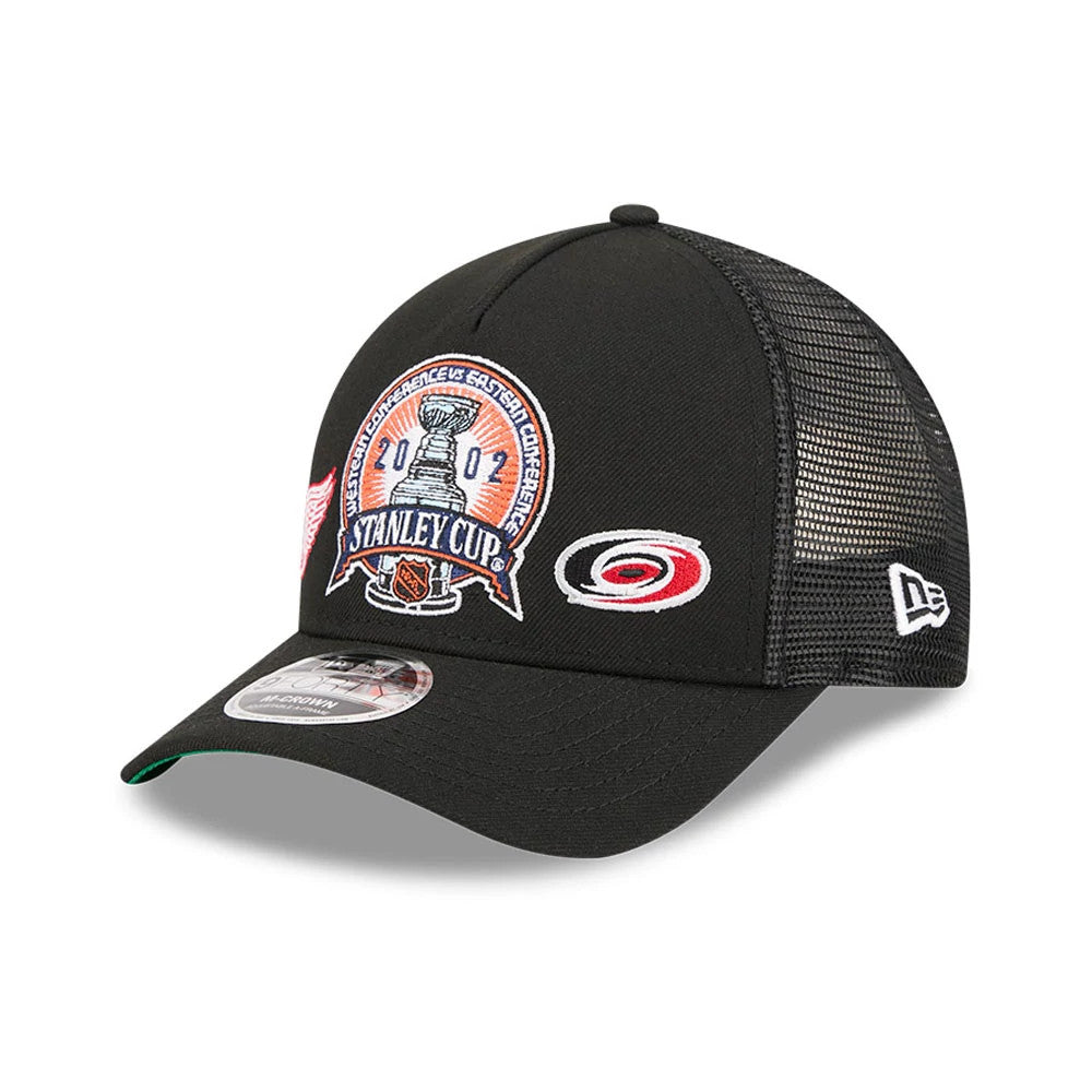 Red Wings NHL Stanley Cup Black New Era 9FORTY M-Crown A-Frame Trucker Adjustable Cap, three-quarter view showing a multi-coloured embroidered Stanley Cup logo on the front panel, a grey mesh back, and a classic New Era flag logo on the left side.